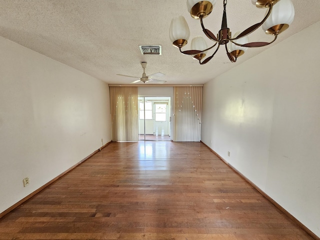 empty room featuring ceiling fan with notable chandelier, a textured ceiling, and hardwood / wood-style flooring