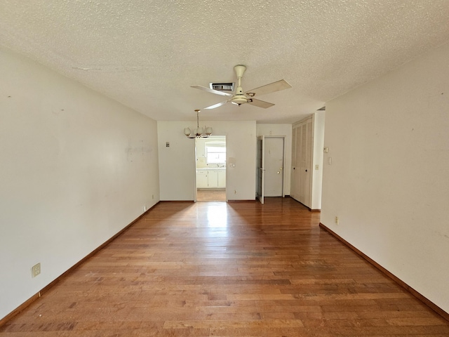 unfurnished room with ceiling fan with notable chandelier, light hardwood / wood-style floors, and a textured ceiling