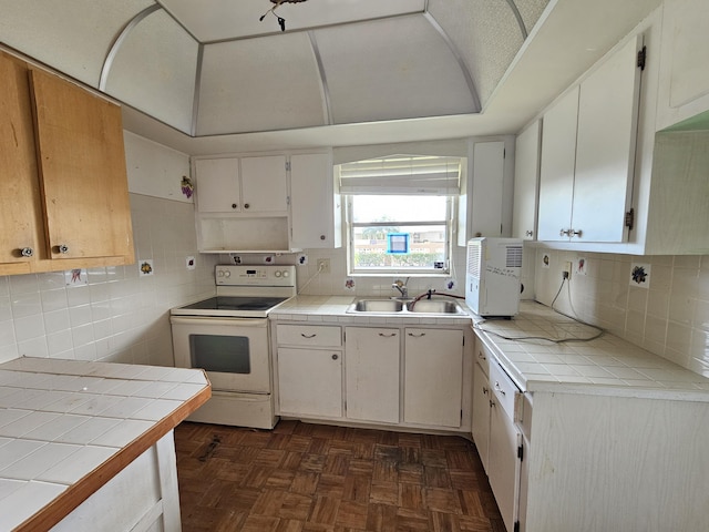 kitchen with tile countertops, dark parquet floors, sink, white electric range oven, and white cabinetry