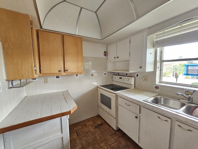 kitchen featuring tile countertops, white cabinets, white electric range, sink, and tasteful backsplash