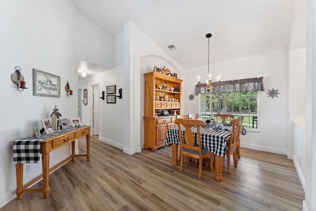 dining area featuring a chandelier, hardwood / wood-style floors, and vaulted ceiling