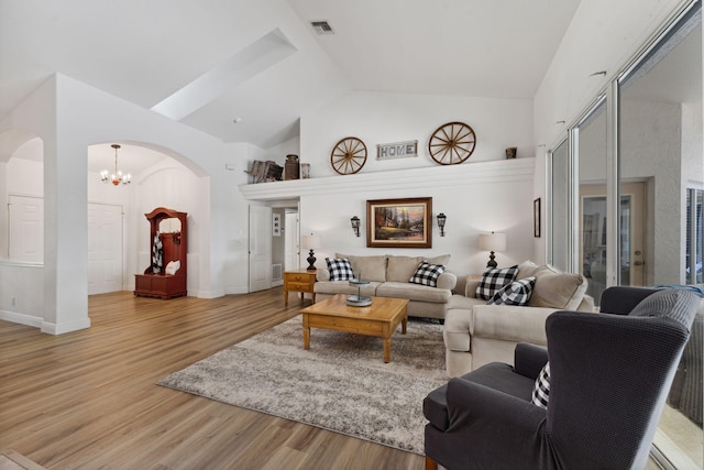 living room featuring hardwood / wood-style floors, high vaulted ceiling, and an inviting chandelier