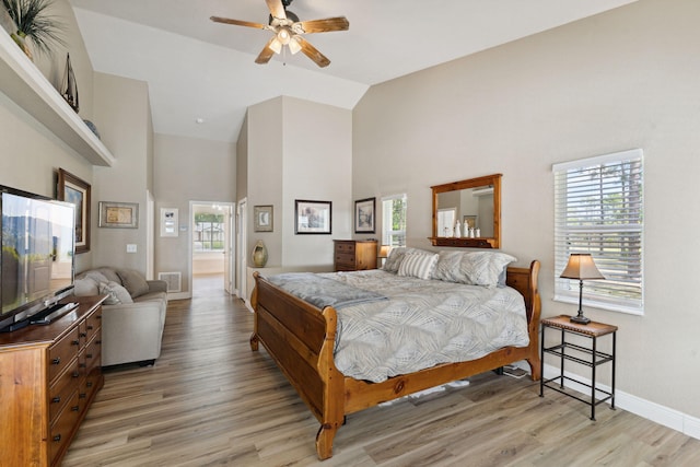 bedroom with connected bathroom, ceiling fan, high vaulted ceiling, and light hardwood / wood-style floors