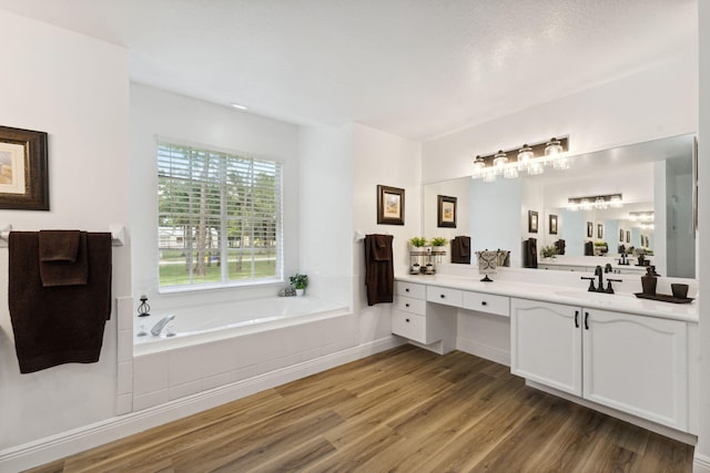 bathroom with vanity, wood-type flooring, and tiled bath