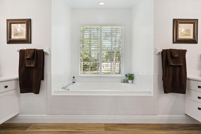 bathroom with vanity, hardwood / wood-style flooring, and tiled tub