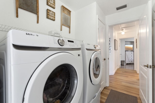 laundry area featuring washing machine and dryer and light wood-type flooring