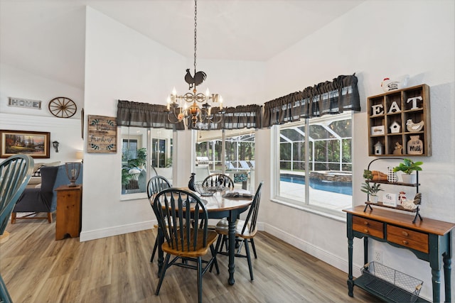 dining space with hardwood / wood-style floors, vaulted ceiling, and a notable chandelier