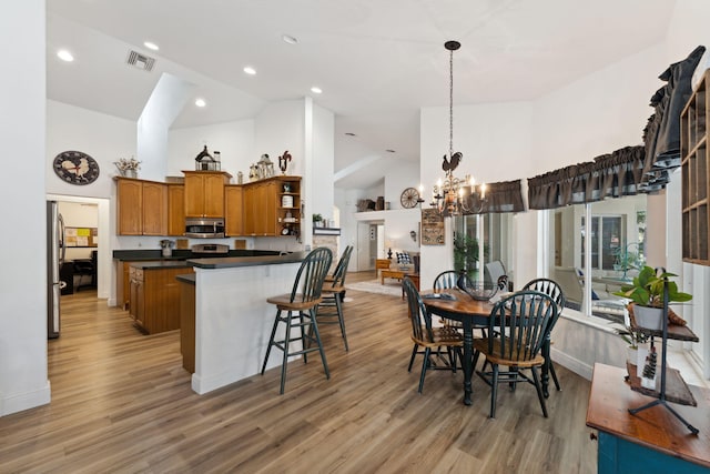 kitchen featuring appliances with stainless steel finishes, light hardwood / wood-style flooring, a kitchen breakfast bar, and a notable chandelier