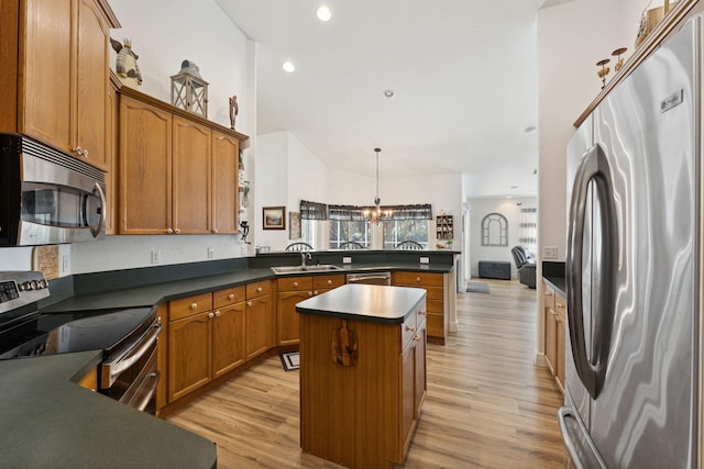 kitchen with appliances with stainless steel finishes, sink, an inviting chandelier, a center island, and hanging light fixtures