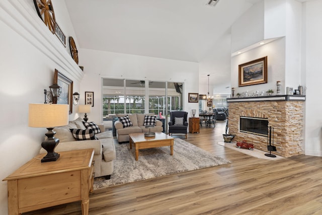 living room with a chandelier, a fireplace, hardwood / wood-style floors, and a high ceiling