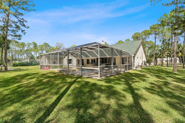 back of house featuring a lawn, glass enclosure, and a patio area