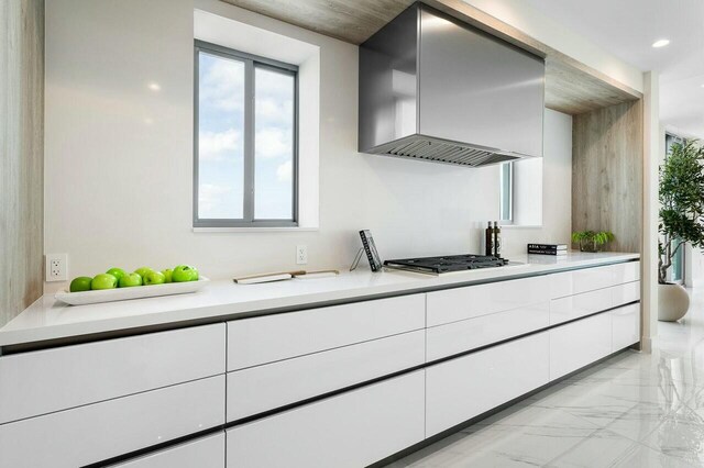 kitchen featuring white cabinets, stainless steel gas cooktop, and wall chimney range hood