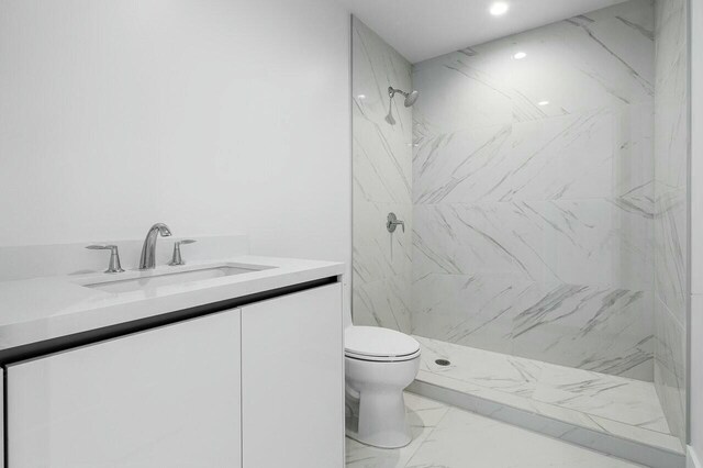 bathroom featuring tiled shower, vanity, and toilet