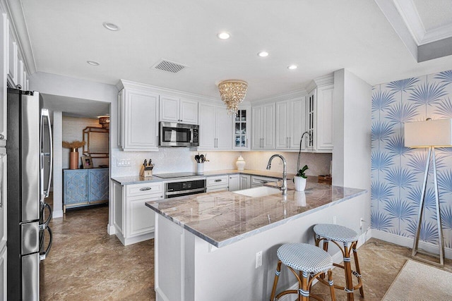 kitchen featuring a breakfast bar, crown molding, kitchen peninsula, white cabinetry, and stainless steel appliances