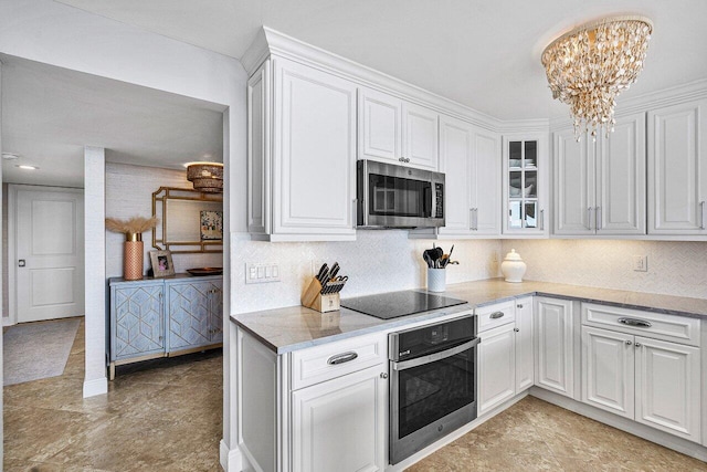 kitchen featuring a chandelier, decorative backsplash, stainless steel appliances, and white cabinetry