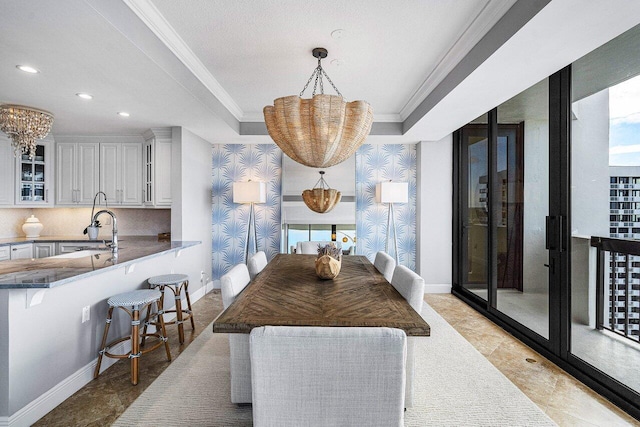 dining room featuring a raised ceiling, an inviting chandelier, crown molding, and sink