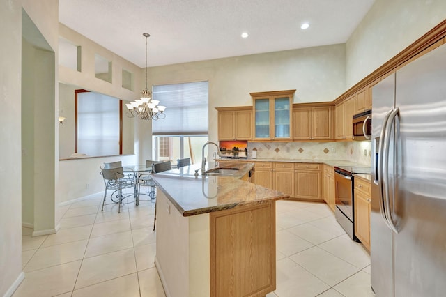 kitchen with sink, hanging light fixtures, an inviting chandelier, light stone counters, and appliances with stainless steel finishes