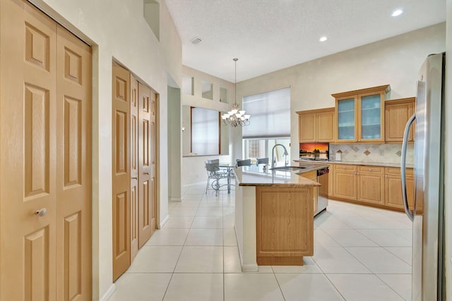 kitchen featuring hanging light fixtures, stainless steel fridge, light tile patterned floors, a notable chandelier, and light stone counters