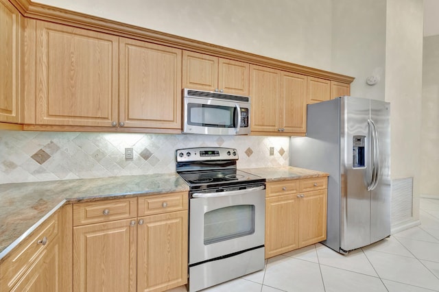 kitchen with decorative backsplash, appliances with stainless steel finishes, light stone counters, and light tile patterned flooring