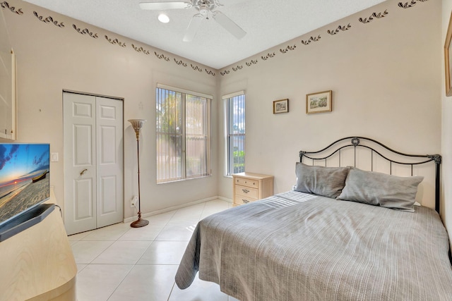 tiled bedroom featuring ceiling fan, a closet, and a textured ceiling