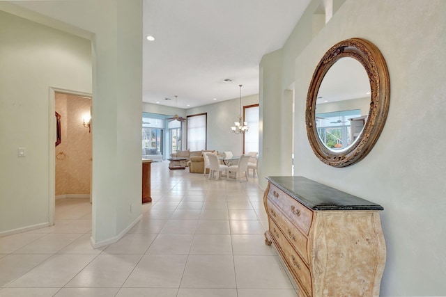 hall featuring light tile patterned floors and an inviting chandelier