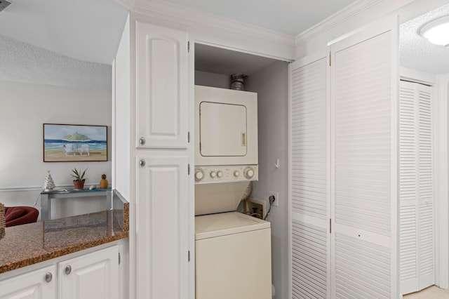 laundry area with a textured ceiling, stacked washer and dryer, and crown molding