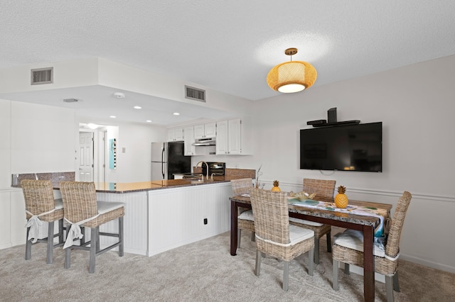 carpeted dining area featuring a textured ceiling