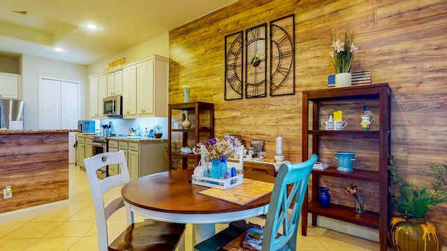 dining space featuring wood walls and light tile patterned floors