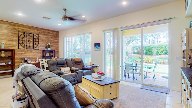 living room with wooden walls, ceiling fan, and light tile patterned flooring