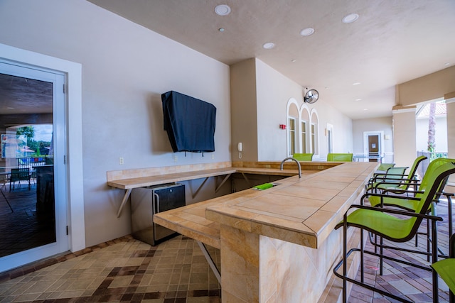 interior space with kitchen peninsula, a breakfast bar, and refrigerator