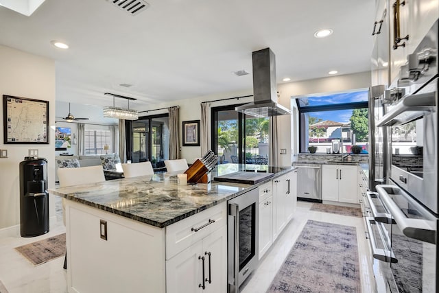 kitchen featuring a kitchen island, stainless steel dishwasher, a kitchen bar, island range hood, and white cabinets