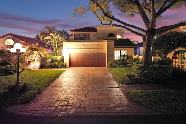 mediterranean / spanish house featuring a garage and a lawn