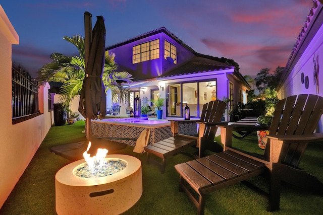 back house at dusk featuring a fire pit and a patio area