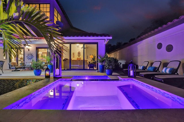 pool at night with an in ground hot tub and a patio