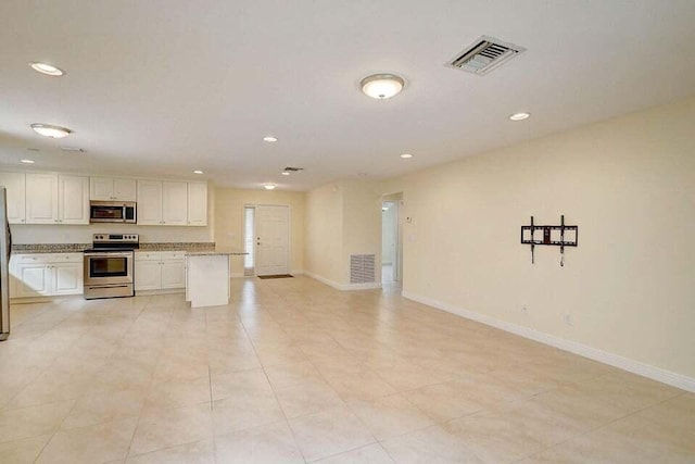 kitchen with white cabinets, light stone counters, light tile patterned floors, and stainless steel appliances