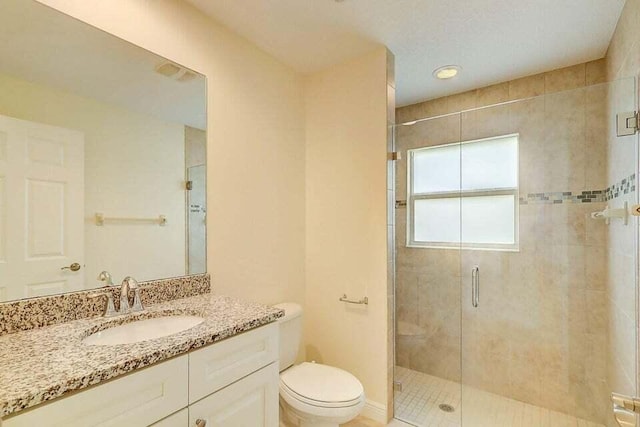 bathroom featuring tile patterned floors, vanity, a shower with shower door, and toilet