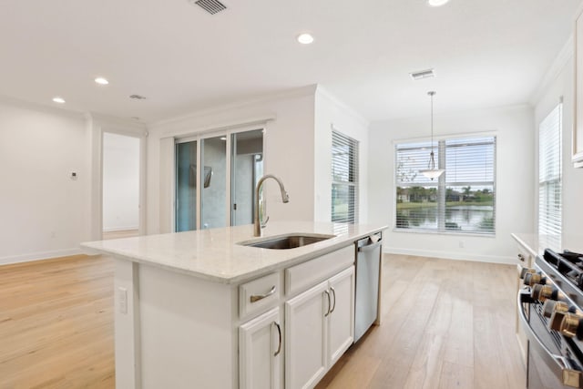 kitchen featuring light stone countertops, stainless steel appliances, sink, a center island with sink, and hanging light fixtures