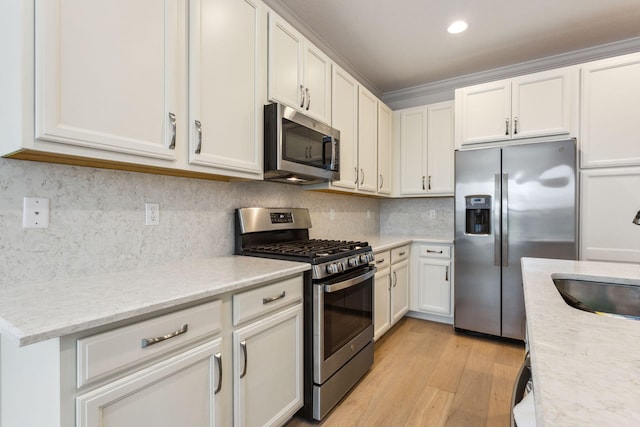 kitchen featuring sink, tasteful backsplash, light stone counters, light hardwood / wood-style flooring, and appliances with stainless steel finishes