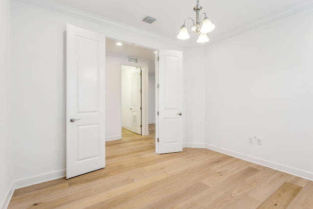 empty room featuring light wood-type flooring, ornamental molding, and an inviting chandelier