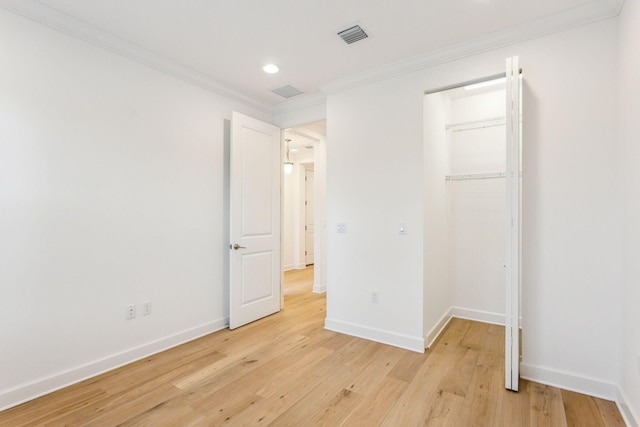 unfurnished bedroom with a closet, crown molding, and light hardwood / wood-style flooring