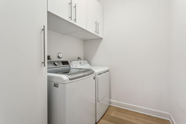 washroom featuring cabinets, light hardwood / wood-style flooring, and washer and dryer