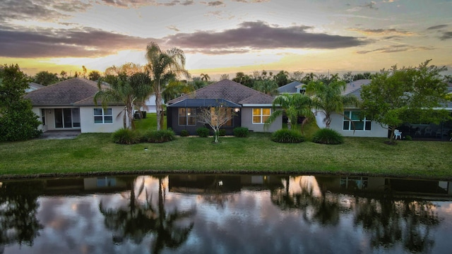 view of front facade featuring a water view and a lawn