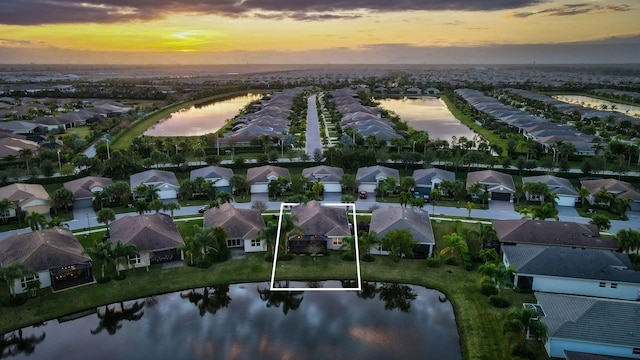 aerial view at dusk featuring a water view