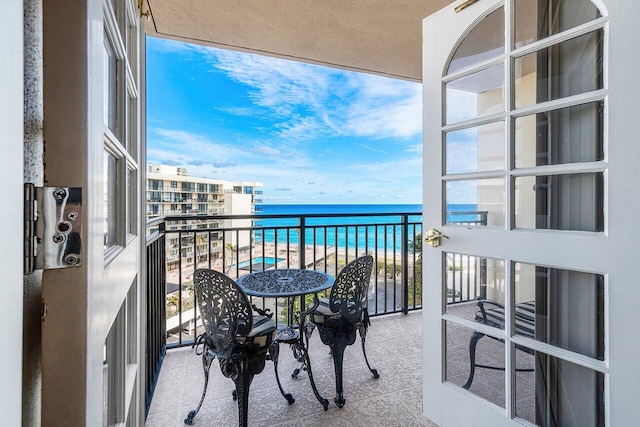 balcony with a water view and a view of the beach