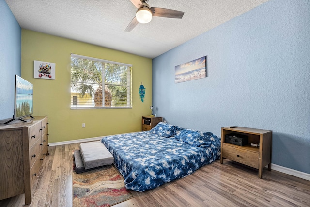 bedroom with hardwood / wood-style floors, ceiling fan, and a textured ceiling