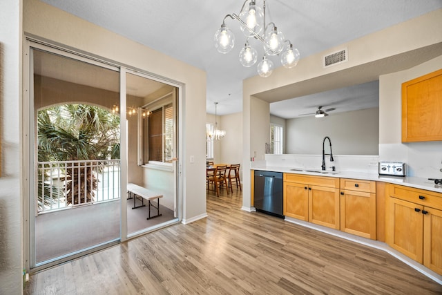 kitchen featuring ceiling fan with notable chandelier, pendant lighting, dishwasher, sink, and light wood-type flooring