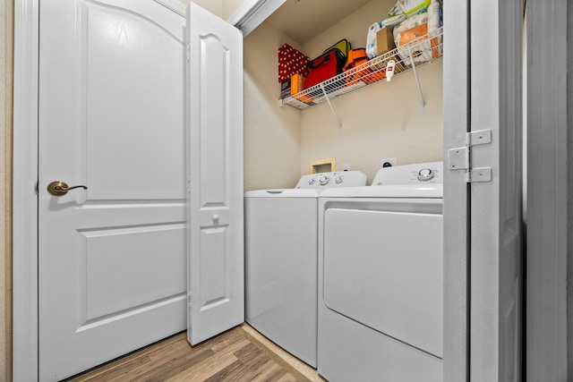 clothes washing area with washing machine and dryer and light hardwood / wood-style flooring