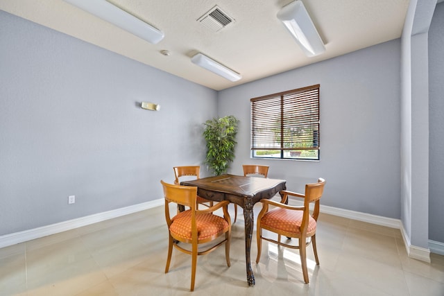 dining space featuring light tile patterned flooring and a textured ceiling