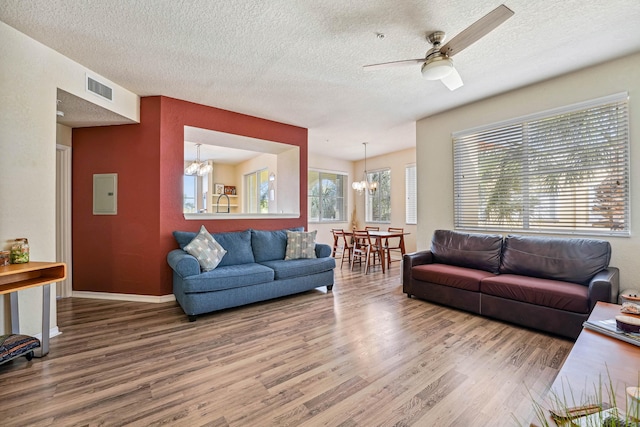 living room featuring a textured ceiling, plenty of natural light, hardwood / wood-style floors, and ceiling fan with notable chandelier