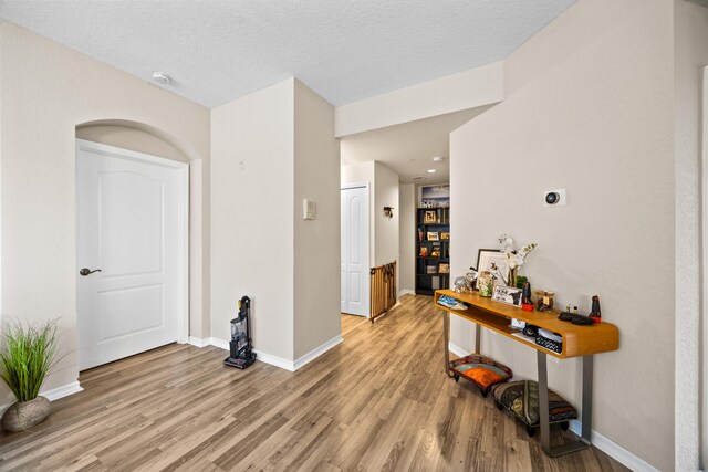 living room with ceiling fan, a textured ceiling, and light wood-type flooring